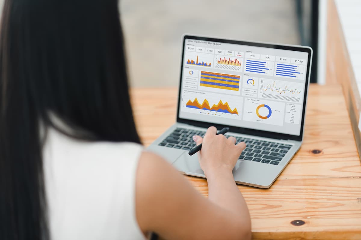 a view of a laptop screen over the shoulder of a woman. The screen displays a crm dashboard